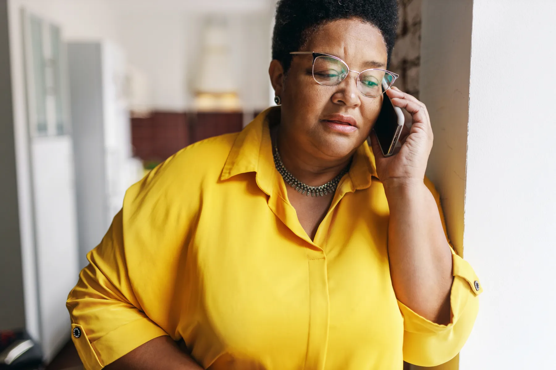 A woman in a yellow shirt listening closely on her phone