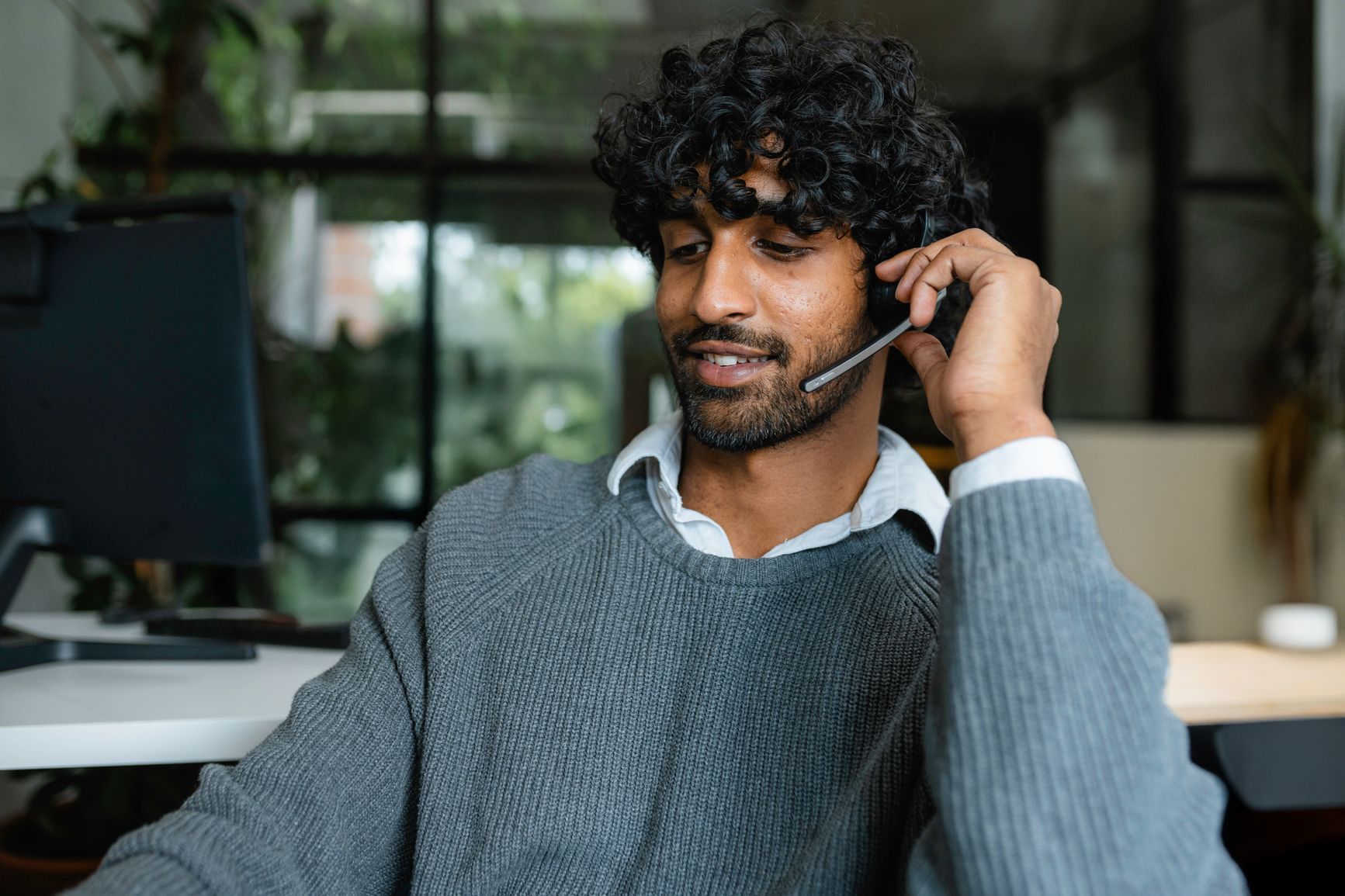 A man using a headset for a call at his computer